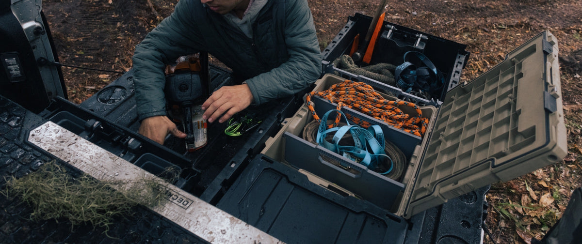 Person organizing outdoor gear in open DECKED storage cases in a truck bed.