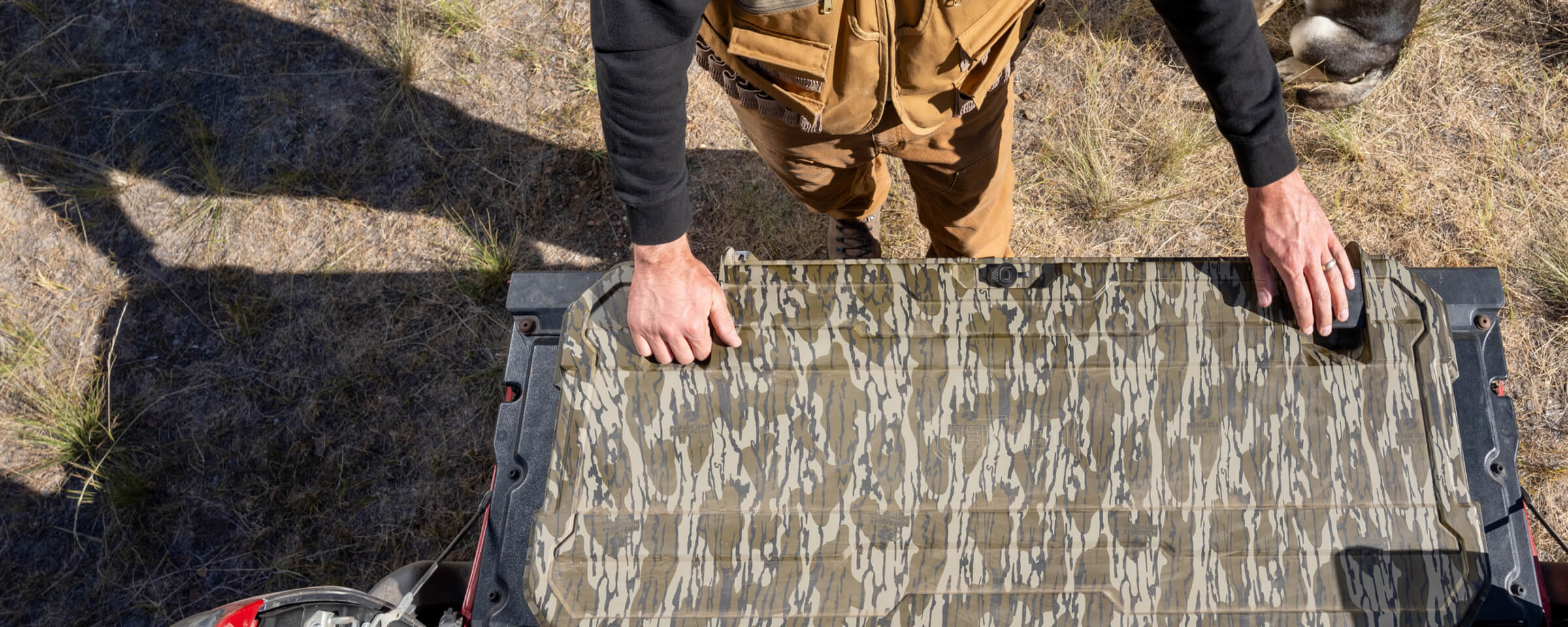 A man grabbing gear out of his DECKED Honcho in Mossy Oak Original Bottomland.