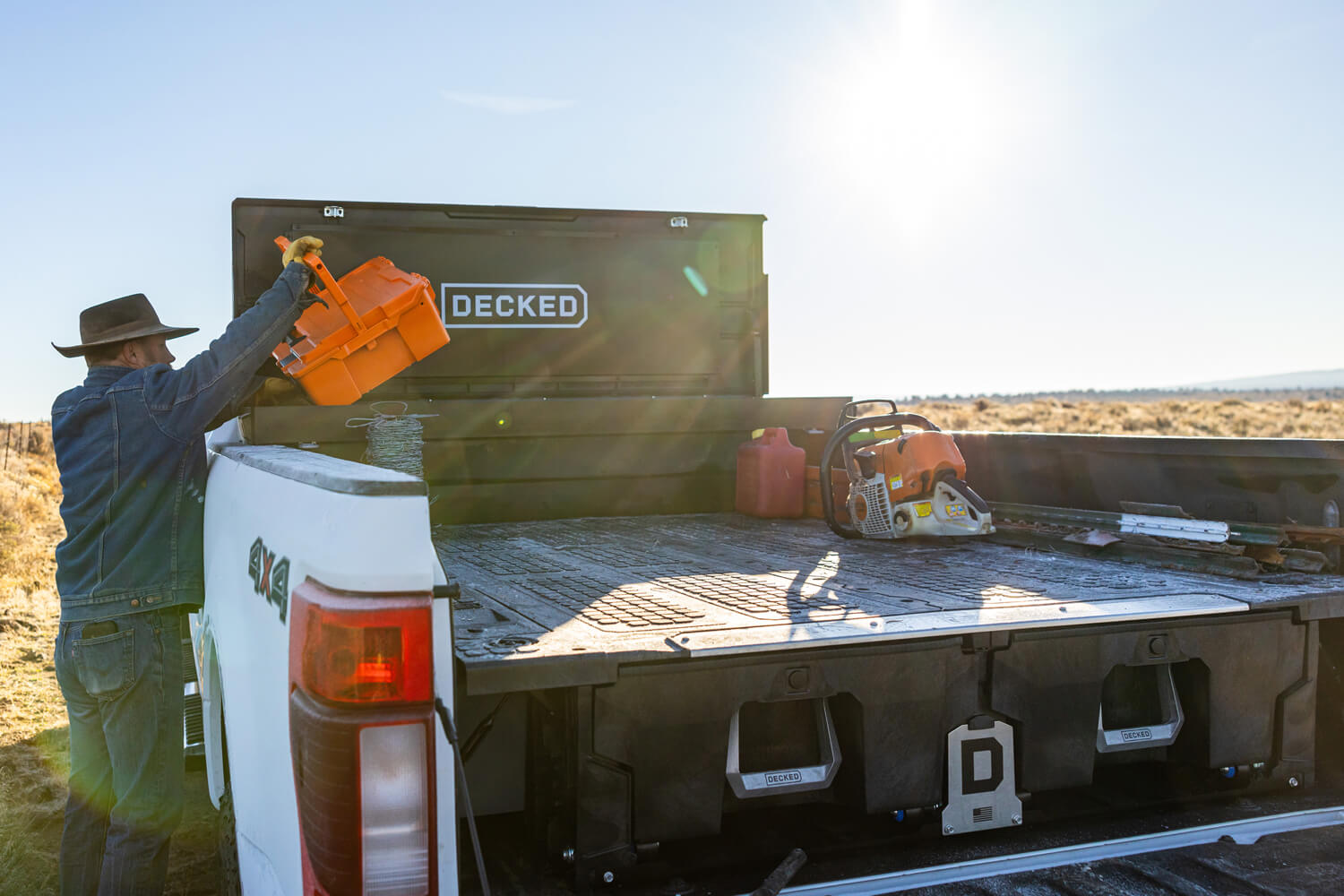 Rancher loading a halfrack into an open black toolbox with an integrated drawer system mounted in the truck bed.