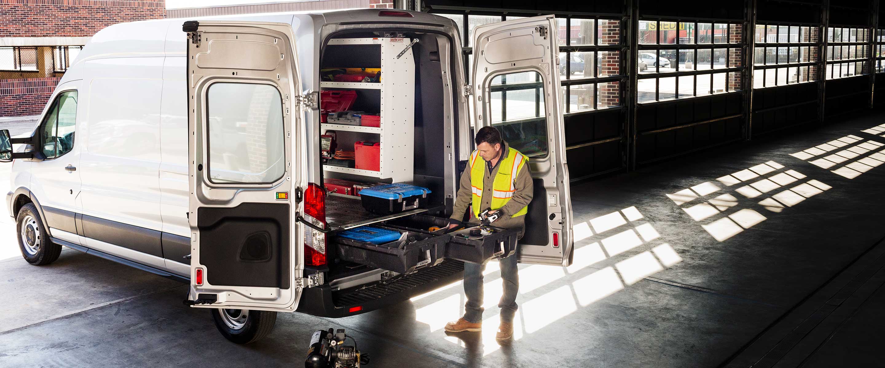 Cargo van with drawer system in the back and man accessing tools