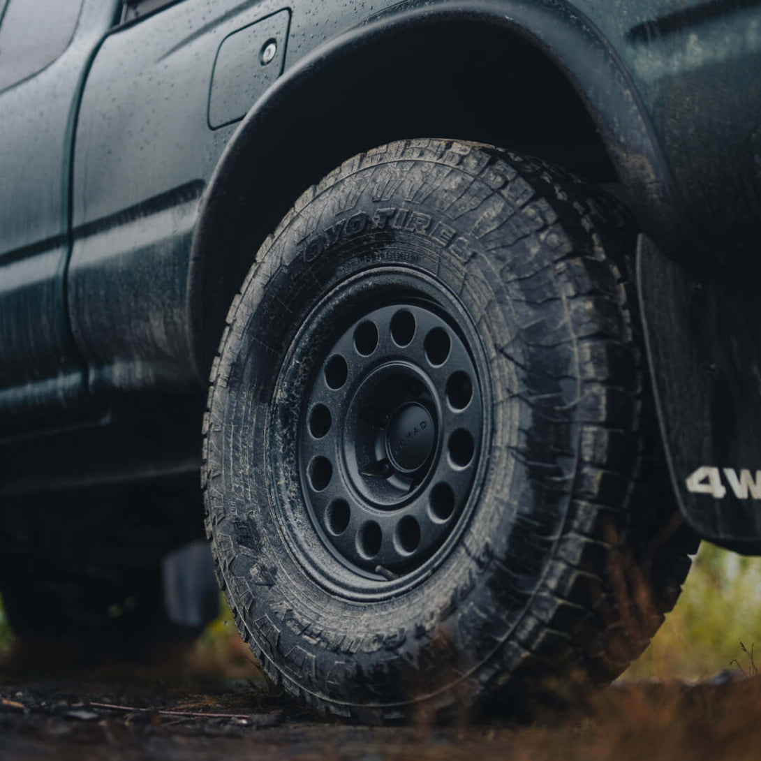 Close-up of a black off-road vehicle tire with mud on a natural terrain