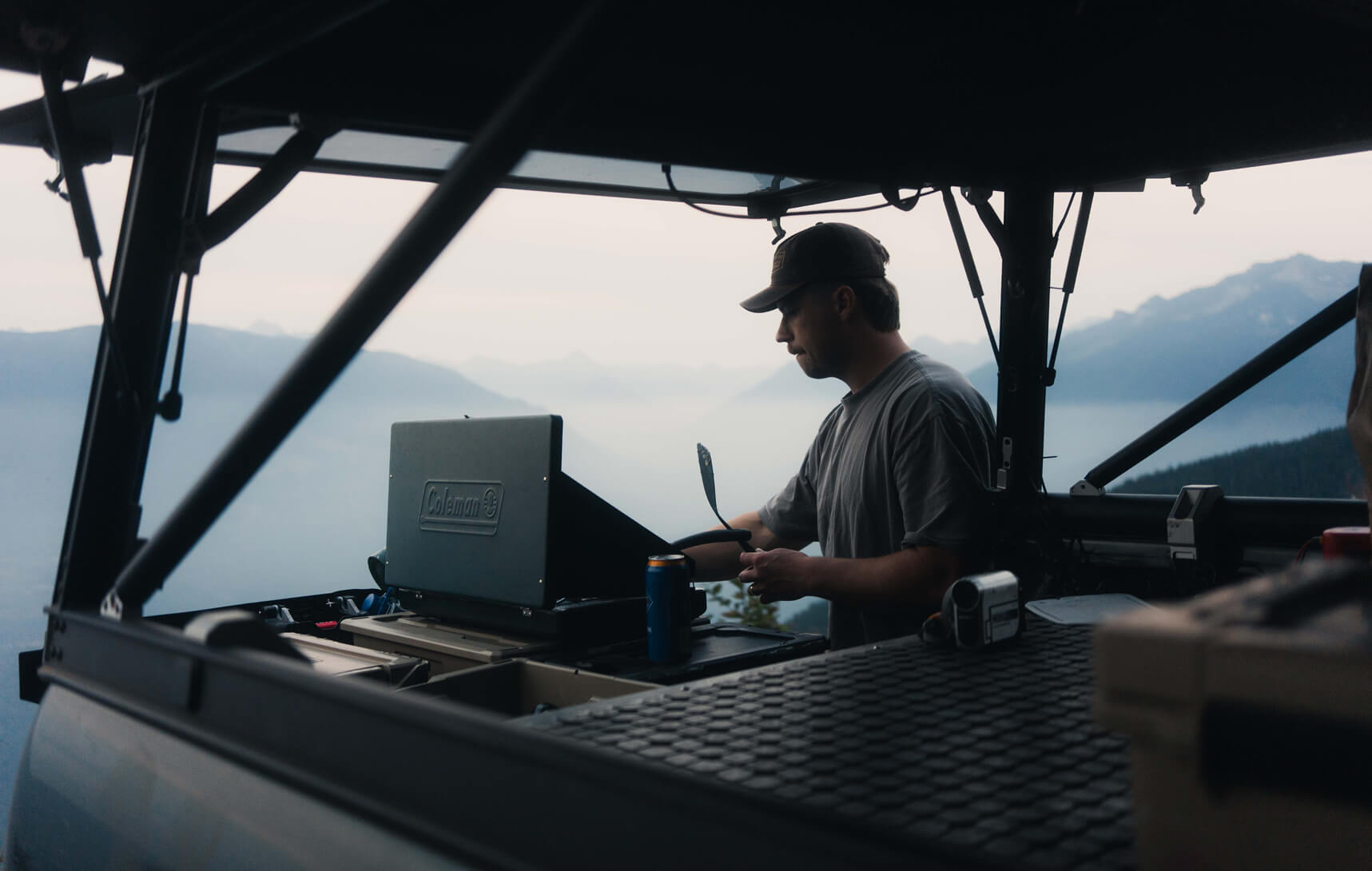 Person cooking dinner in an open vehicle with a Drawer System - scenic mountains are in the background