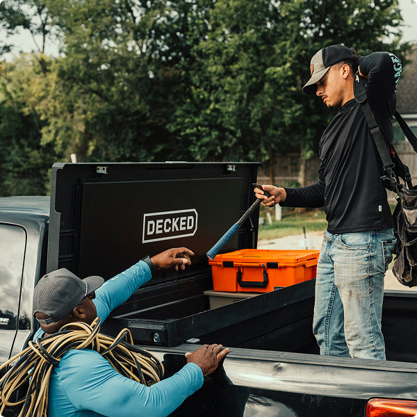 Two men unloading tools from DECKED toolbox at a construction site.