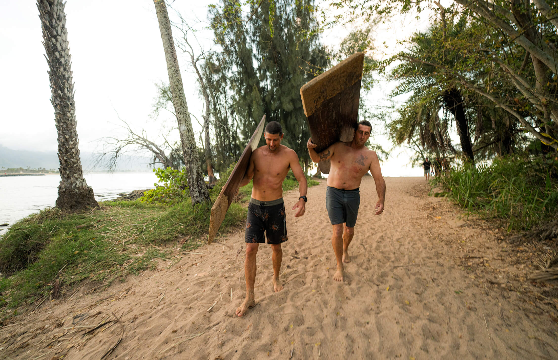 Danny Bolton and Ben Wilkinson carrying slabs of wood that are soon-to-be surfboards.