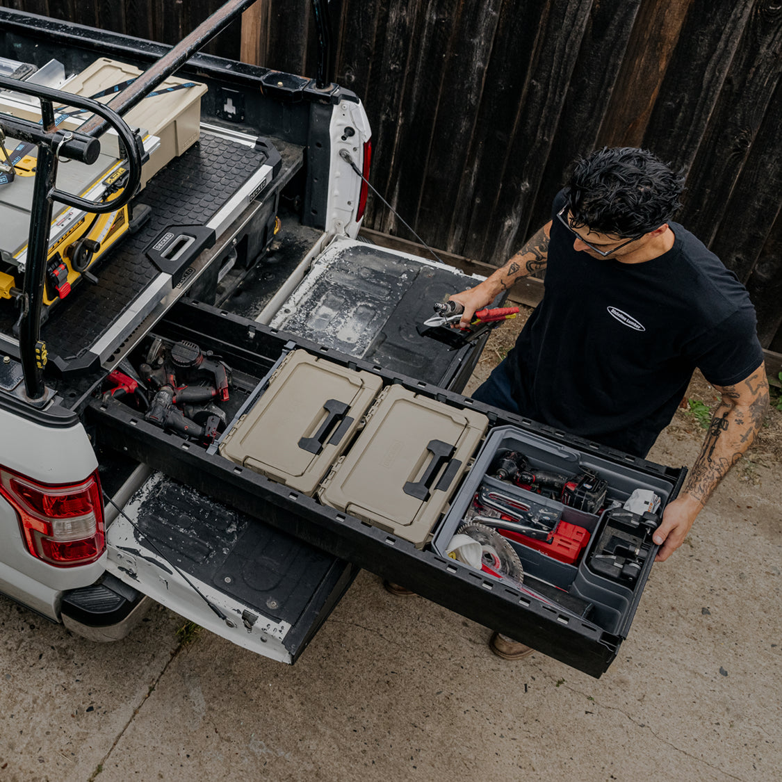 Contractor accessing organized tools and DECKED cases from open Drawer System drawers beneath a CargoGlide.