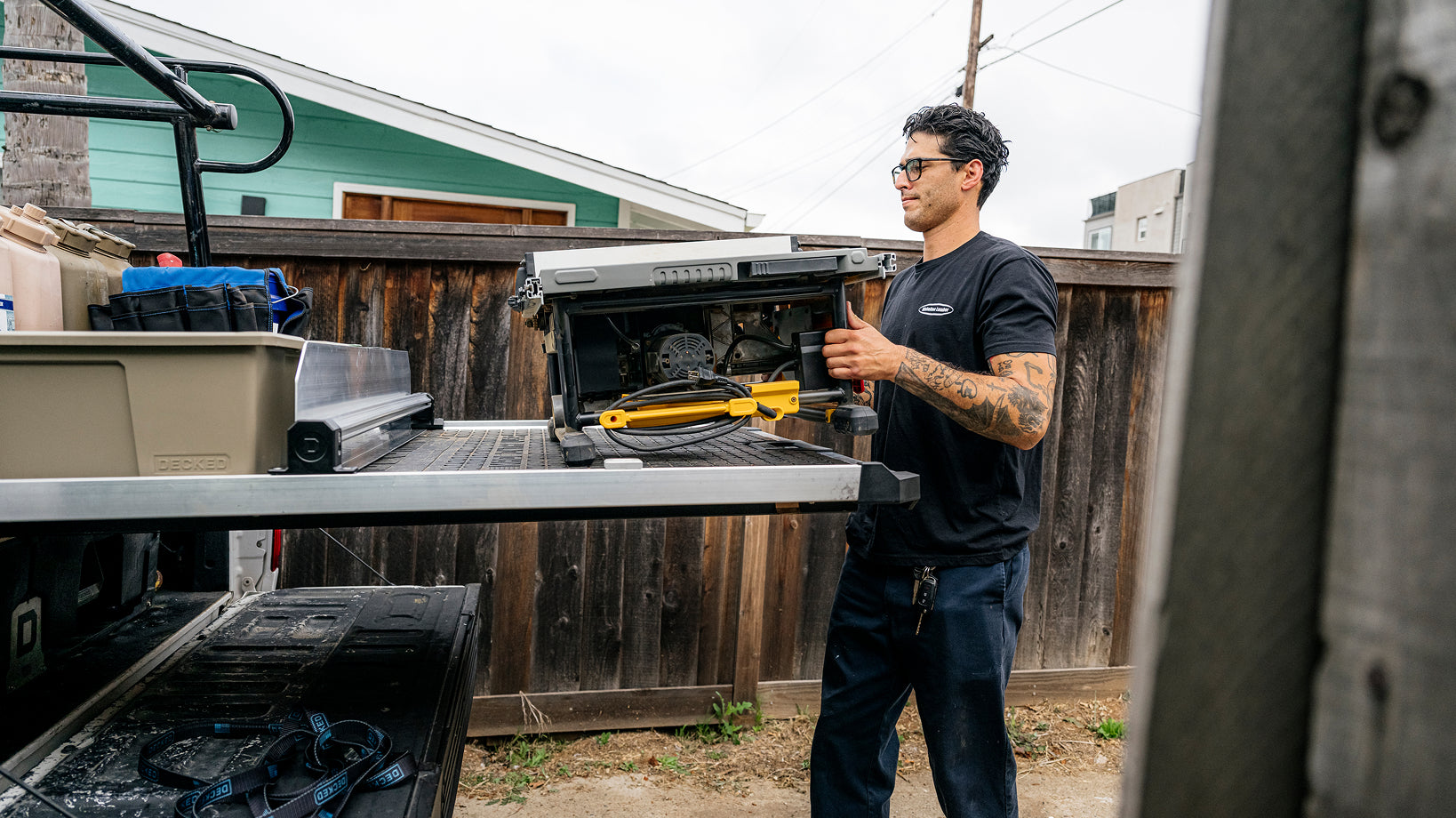 Contractor loading a table saw onto a Man loading heavy equipment DECKED CargoGlide in a pickup truck bed.