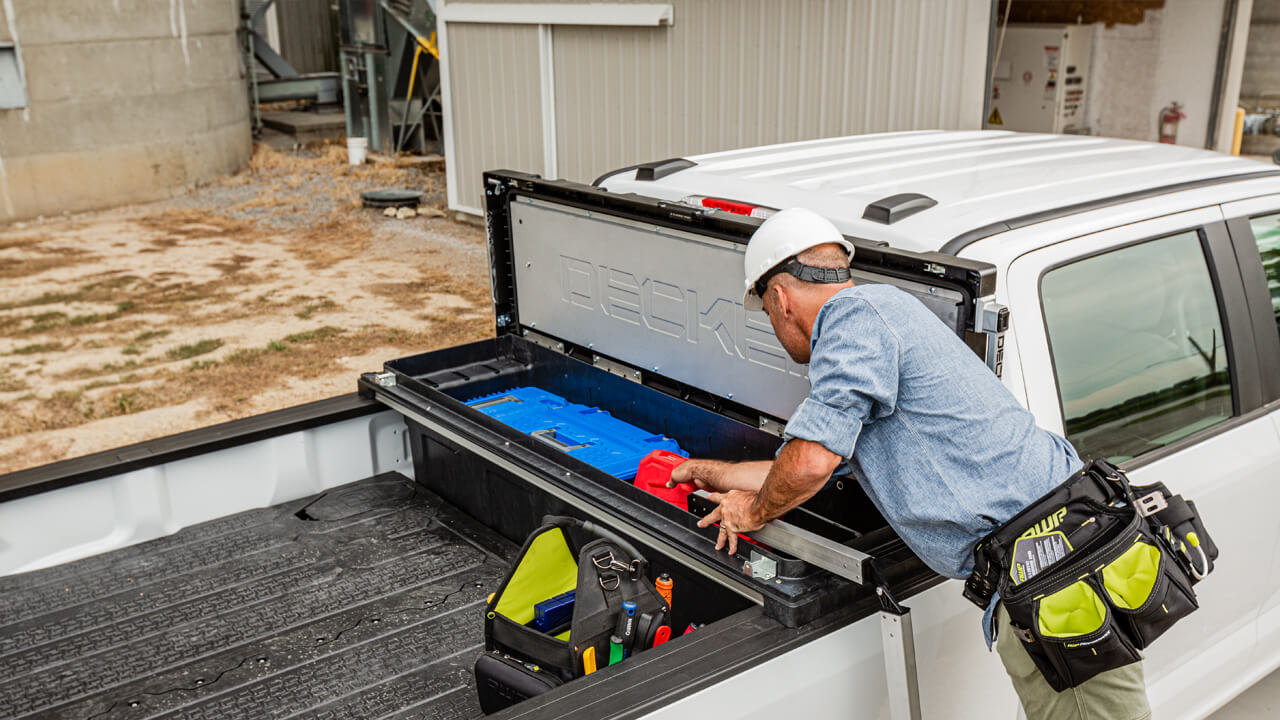 Man grabbing tools out of a decked tool box in the back of a truck