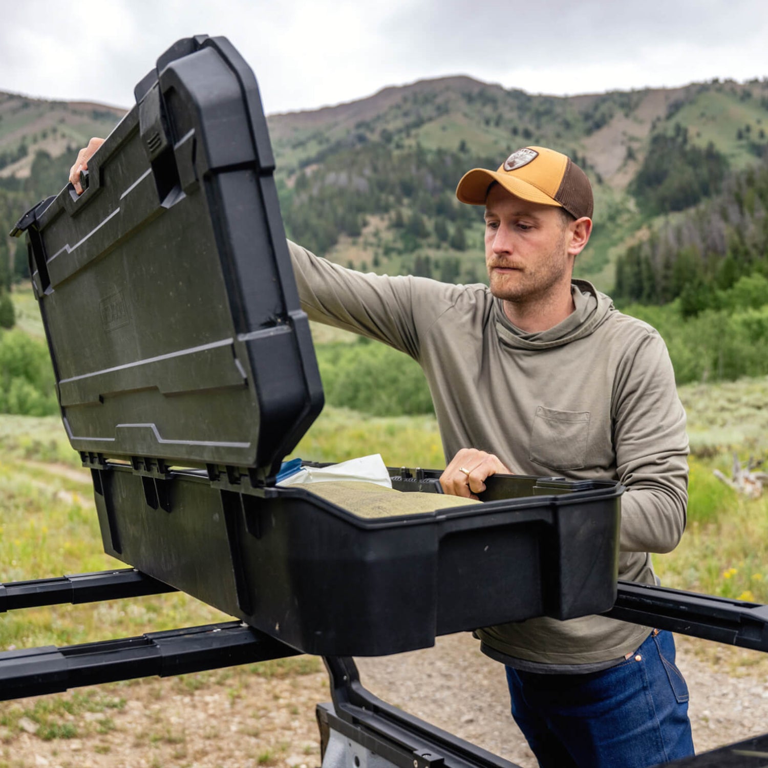 A man retrieving gear out of the black Honcho D-co Case mounted to his roof rack.