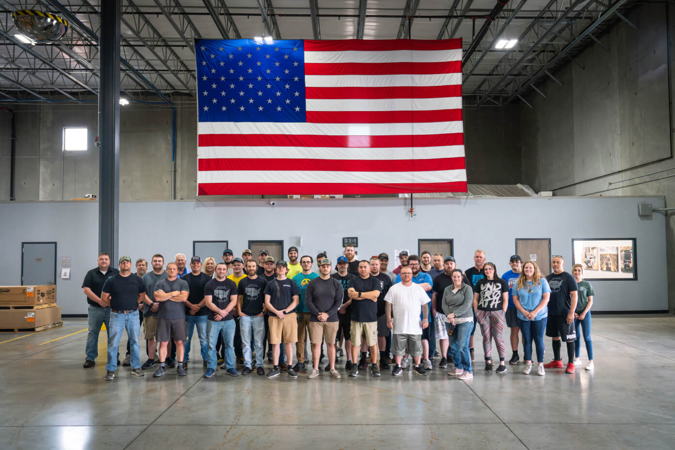 DECKED Ohio employees standing in front of a giant American Flag hanging inside of the manufacturing center.