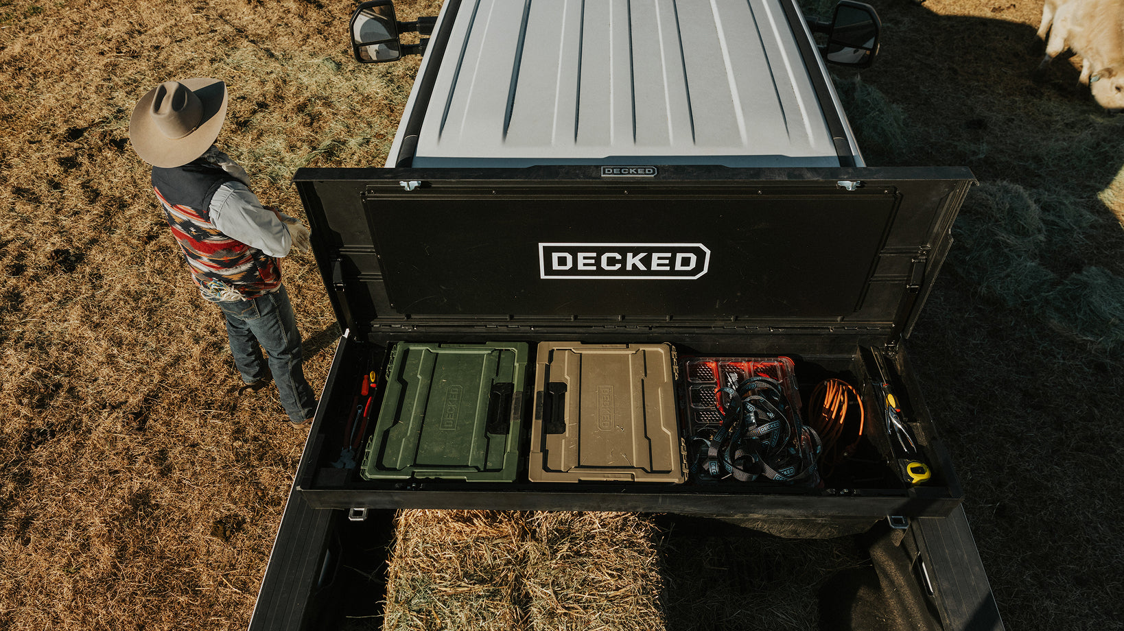 White truck on a ranch with an open toolbox with DECKED halfracks and ranch gear loaded inside.