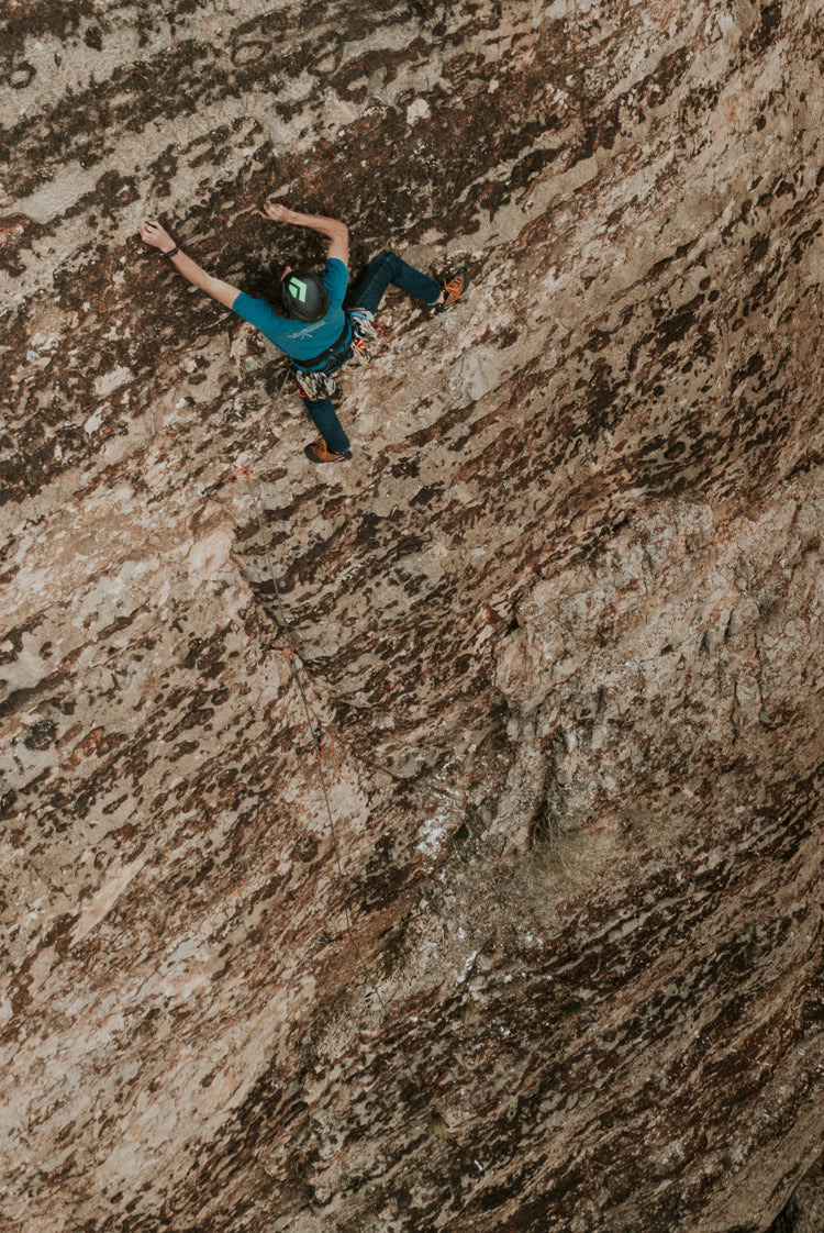 Jackson climbing up a rock face in the desert.