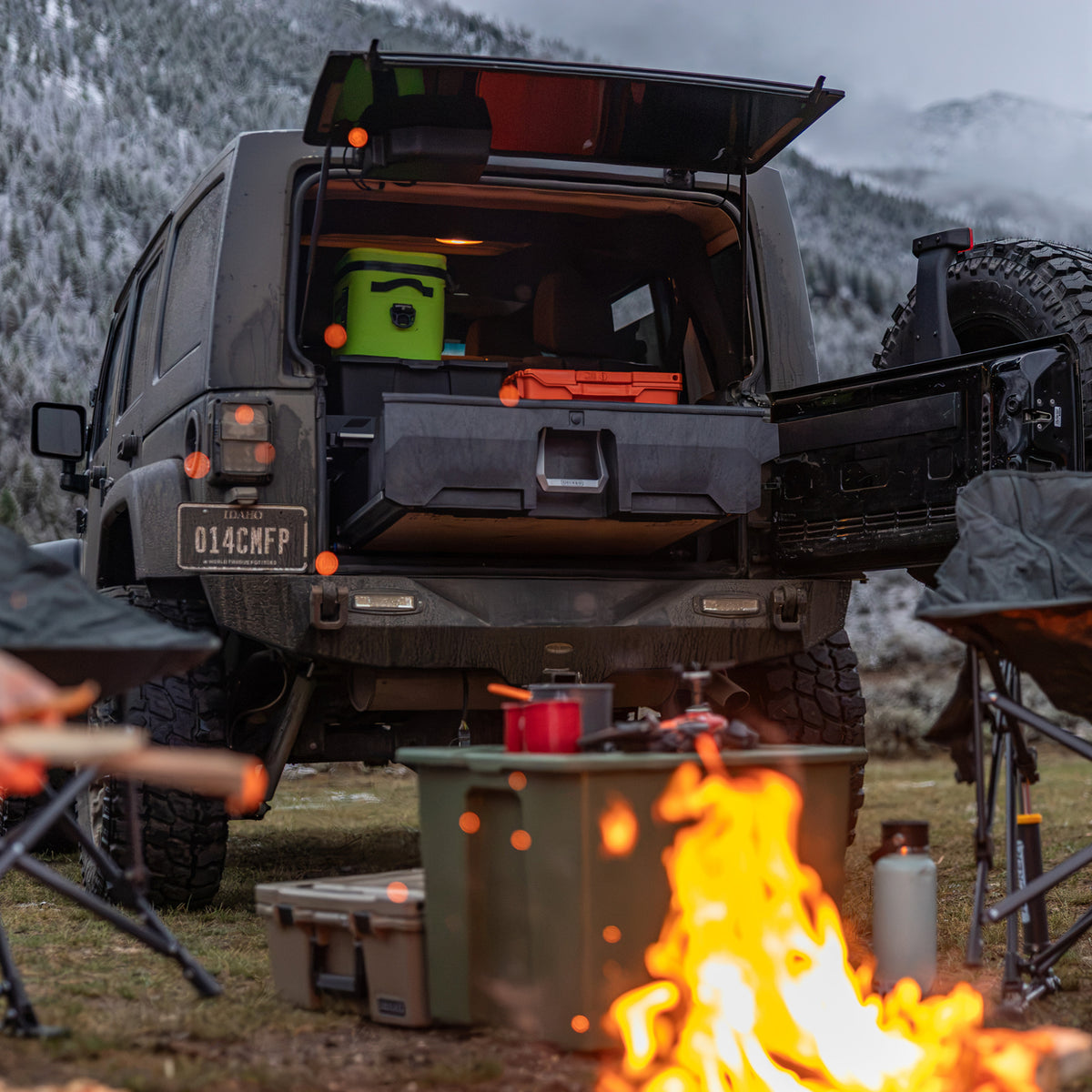 Jeep Wrangler with a DECKED Drawer System and camping gear parked behind a campfire.