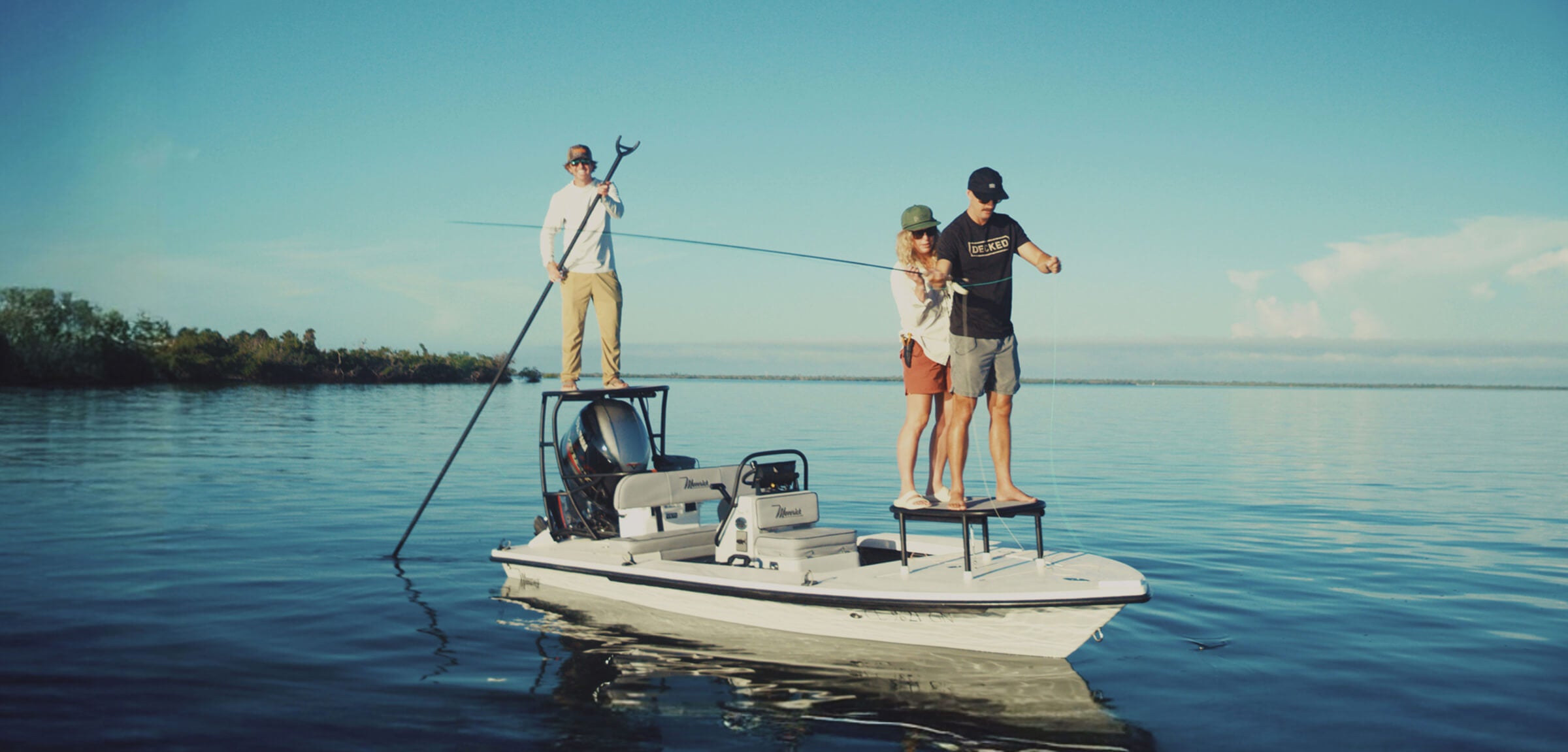 Three people on a small boat in a calm body of water with a clear sky.