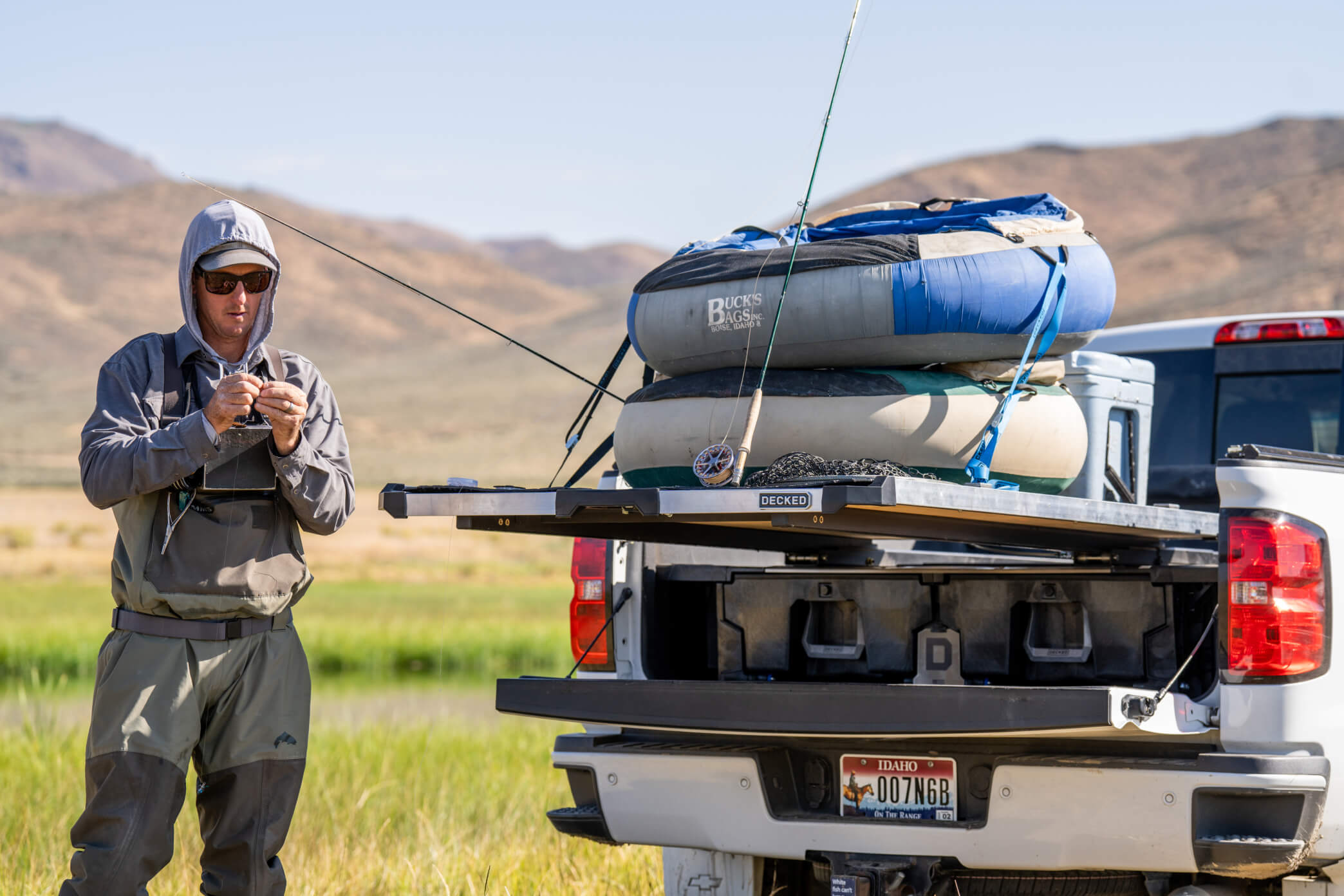 A fisherman standing next to his CargoGlide and Drawer System that is loaded down with rods, float tubes, and a cooler.