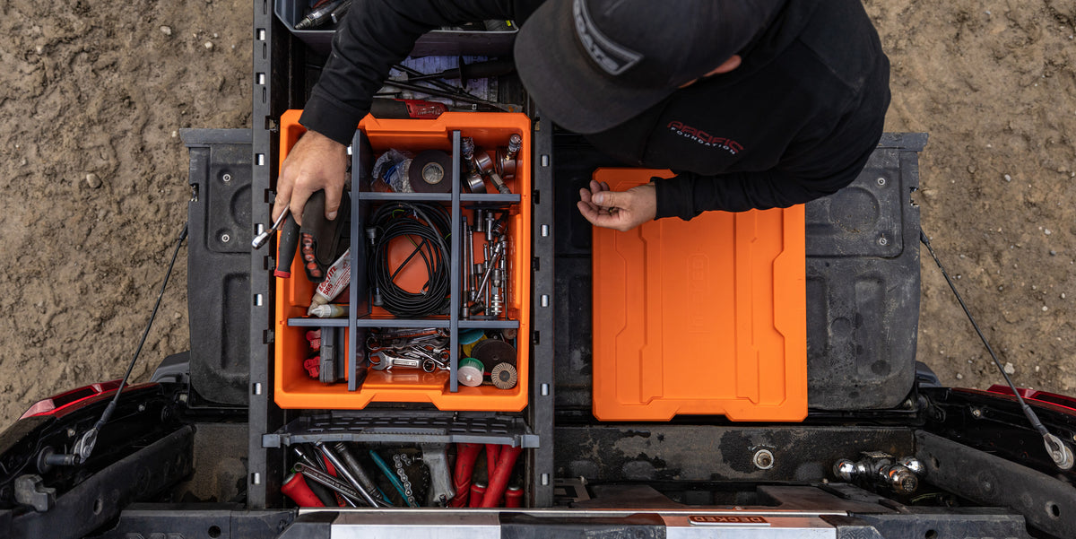 Overhead view of a worker organizing tools and accessories in a DECKED Payloader using the customizable POD divider system.