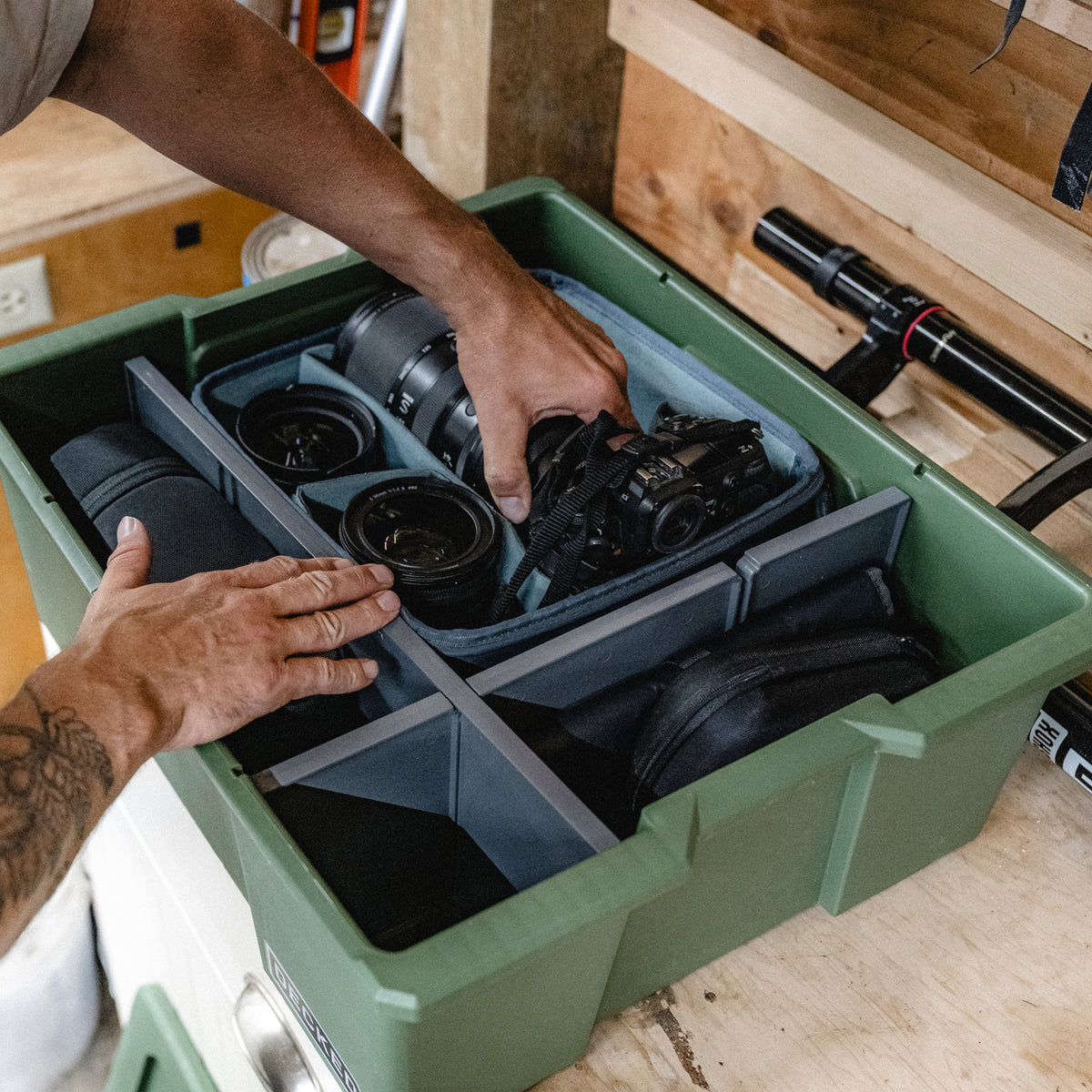 Person organizing cameras, lenses, and accessories inside a DECKED Payloader using the customizable POD divider system.