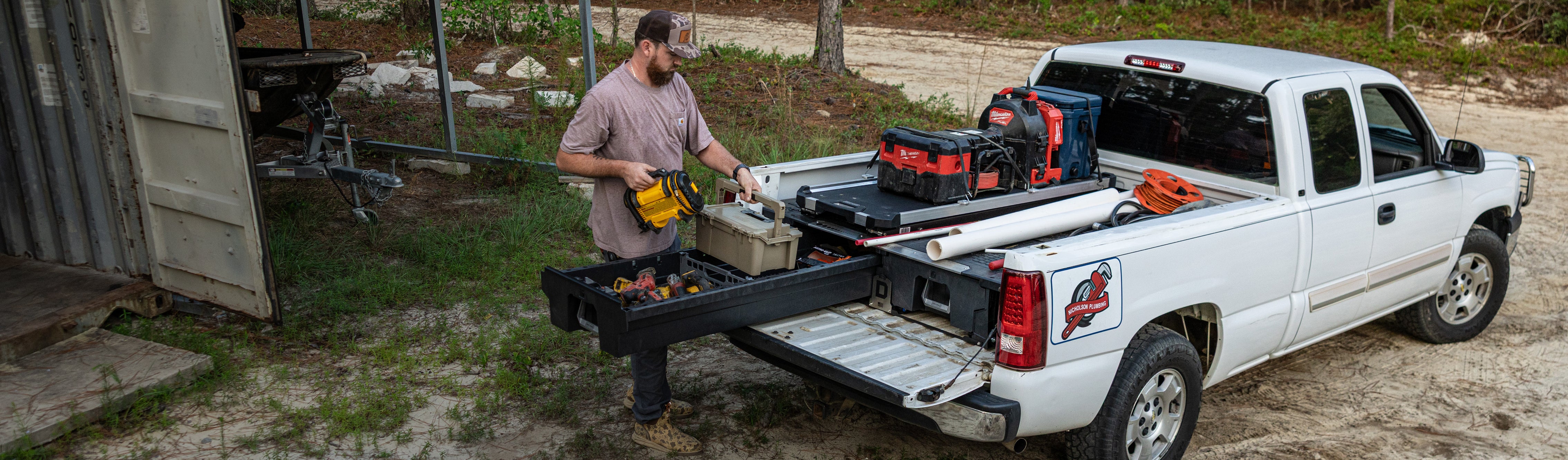 Plumber accessing organized power tools and a DECKED case from a Drawer System beneath a CargoGlide.