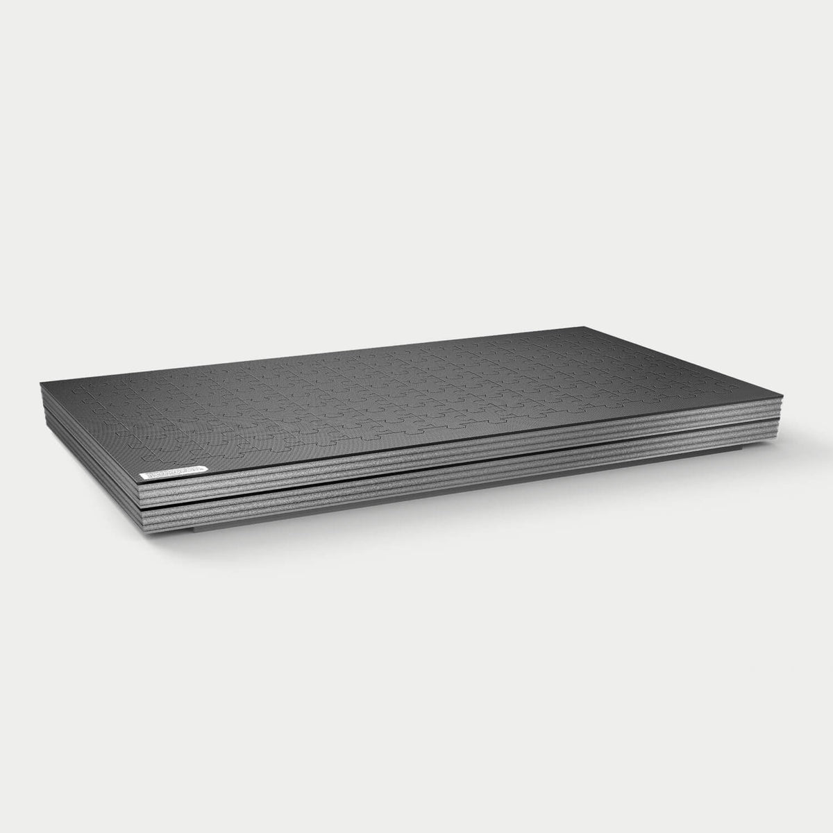 Side view of a flat, layered DECKED puzzle foam block with a textured interlocking jigsaw pattern on top.