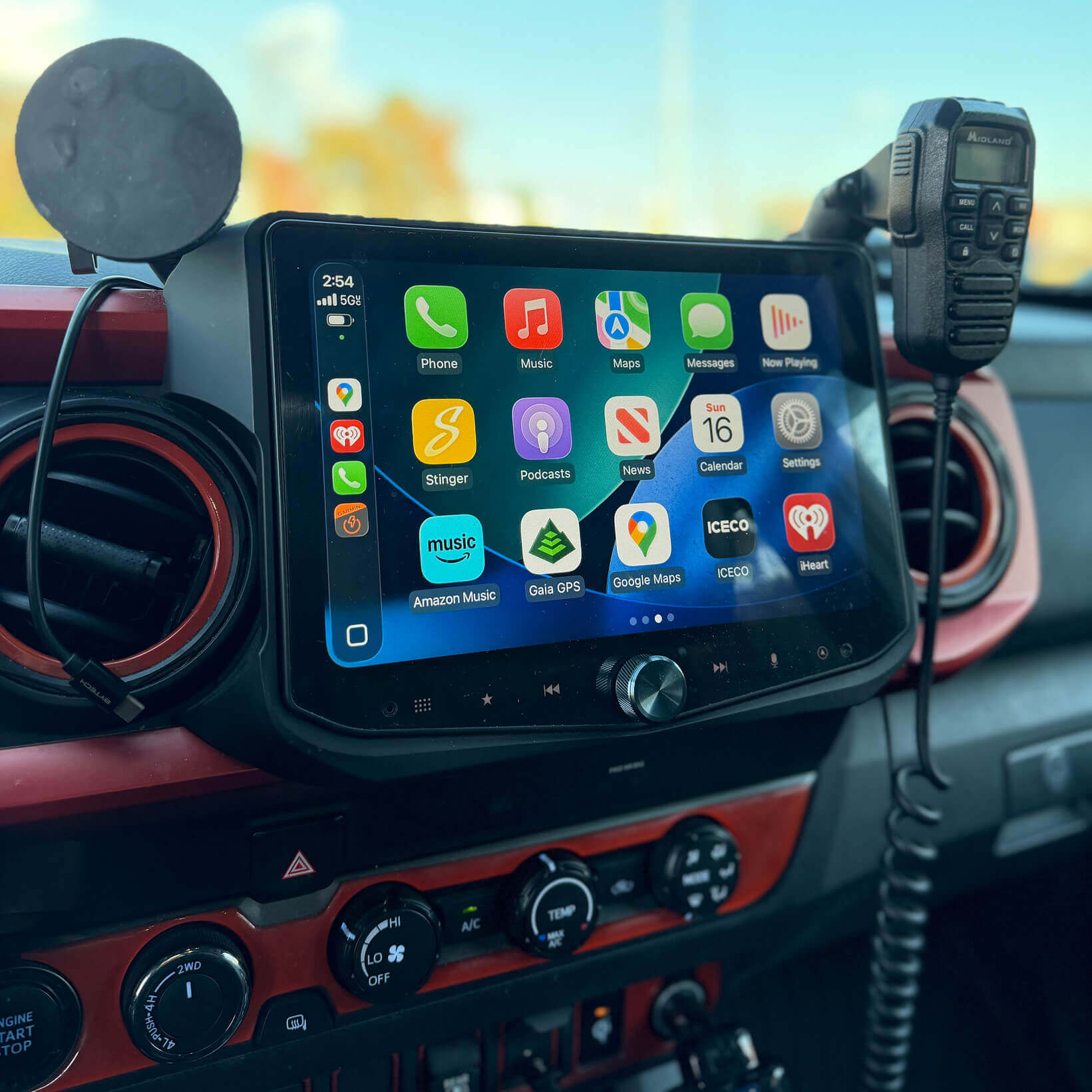 Car dashboard with a touchscreen display showing app icons, surrounded by car interior elements.
