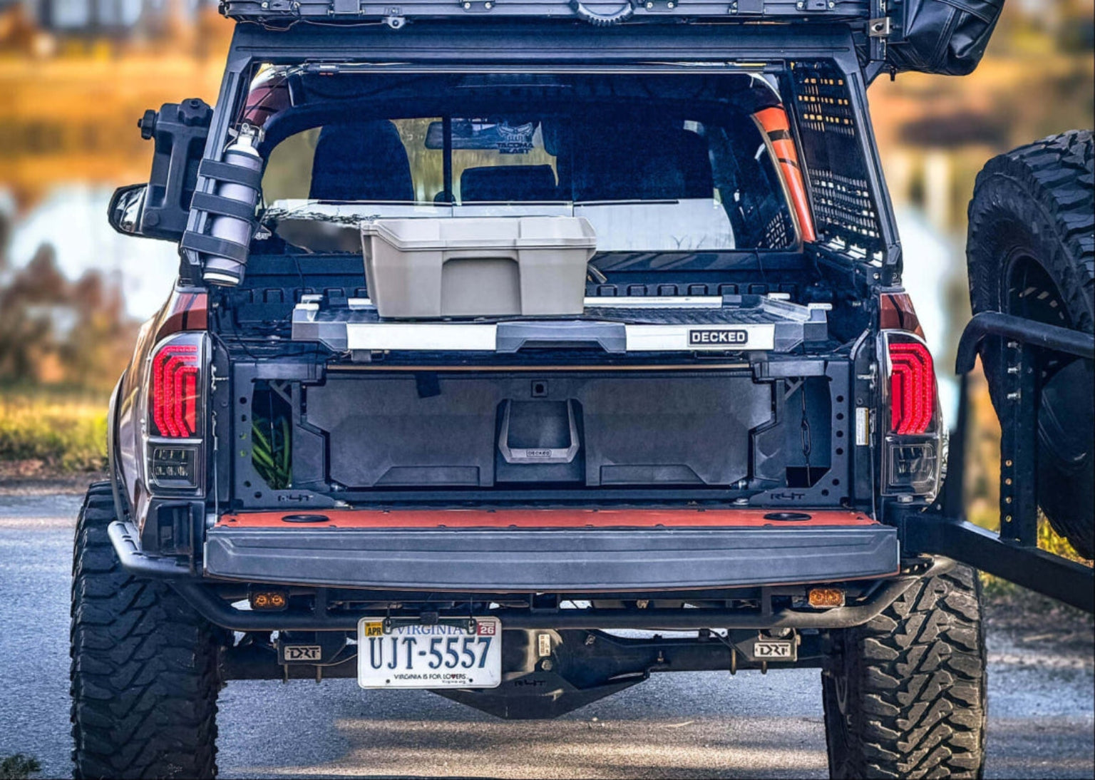 Trunk of a vehicle with storage compartments and a toolbox, outdoors.