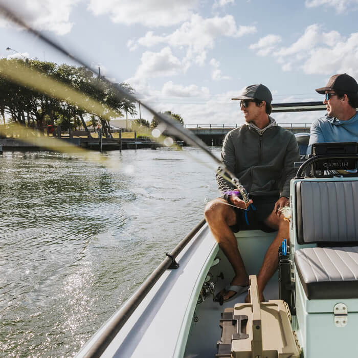 Two men on a boat fishing with a clear sky and water background