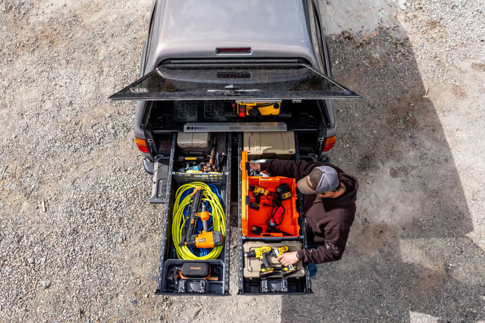 Person organizing tools in a truck bed with open drawers