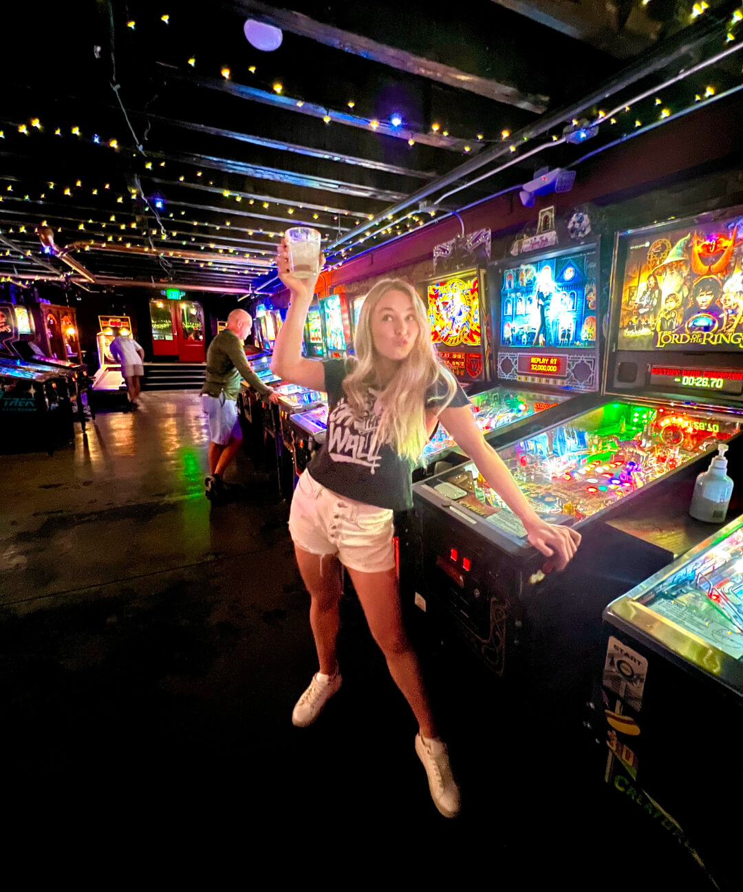 Jen cheers-ing the camera in a pin ball arcade.