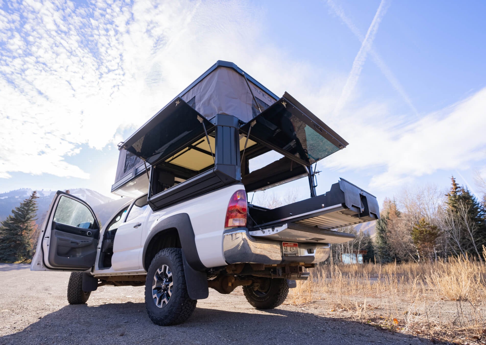 White truck with an open pop-up camper in a mountainous area