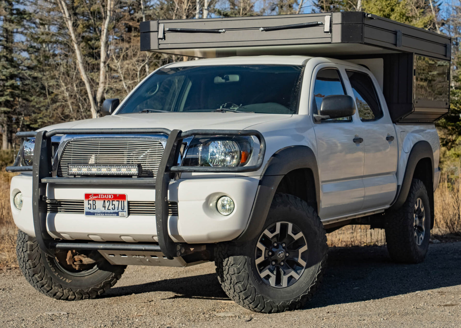 White truck with a bed cover in a natural setting
