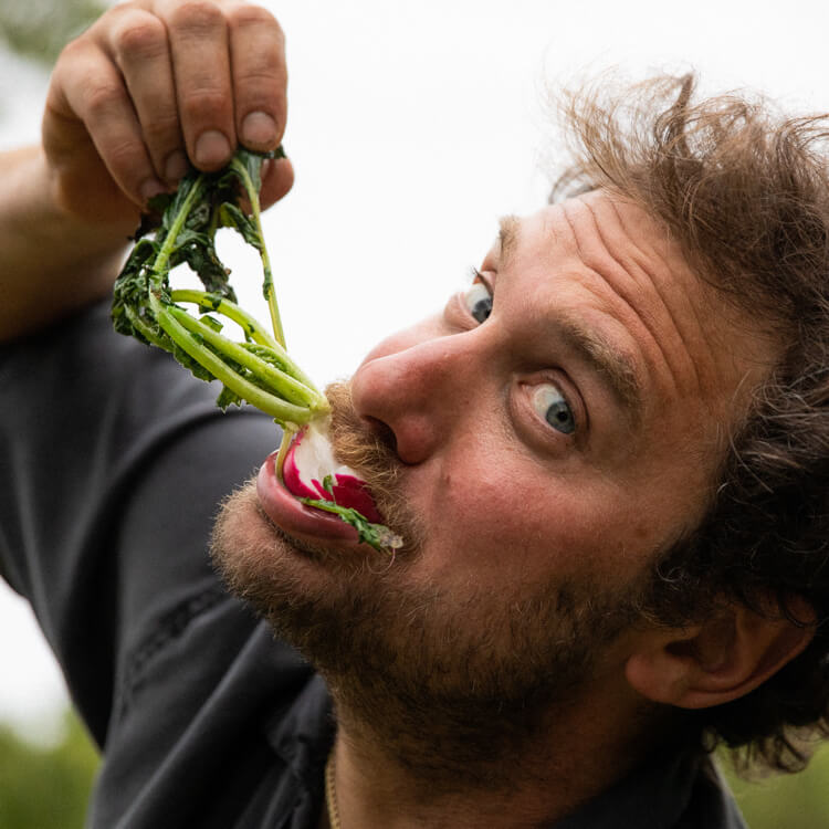 Brad Leone snacking on a turnip he pulled fresh from the garden.