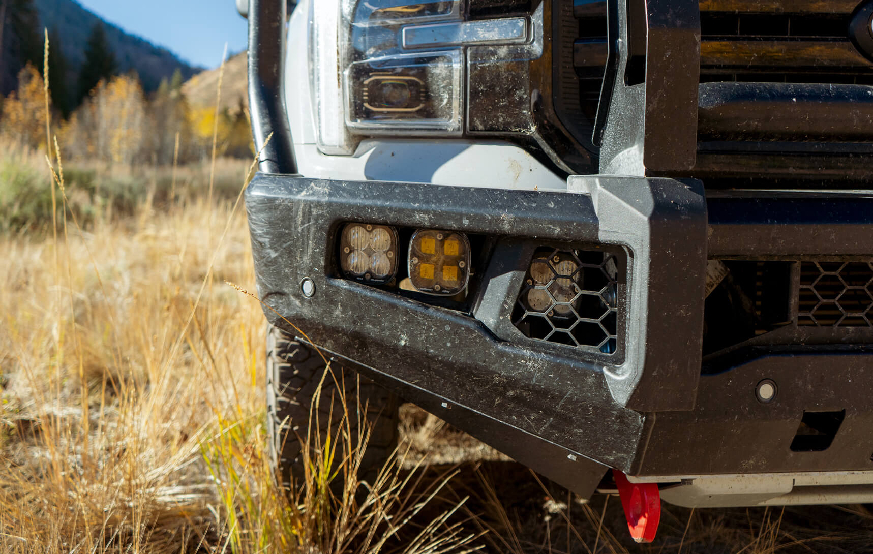Close-up of a vehicle's front bumper with lights in a natural setting