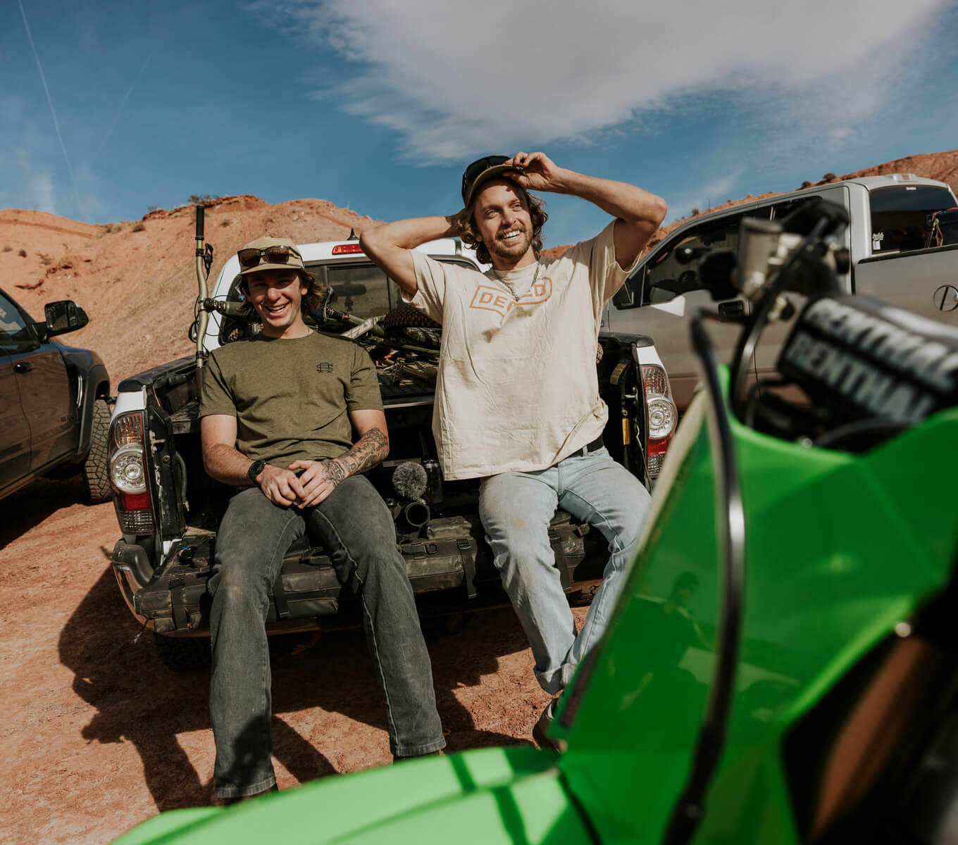 Two guys sitting on their tailgate leaning agains their Decked Drawer System after a day on mountain and moto bikes.