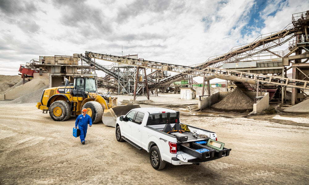 man wearing a blue jumpsuit walks towards his truck on a construction site