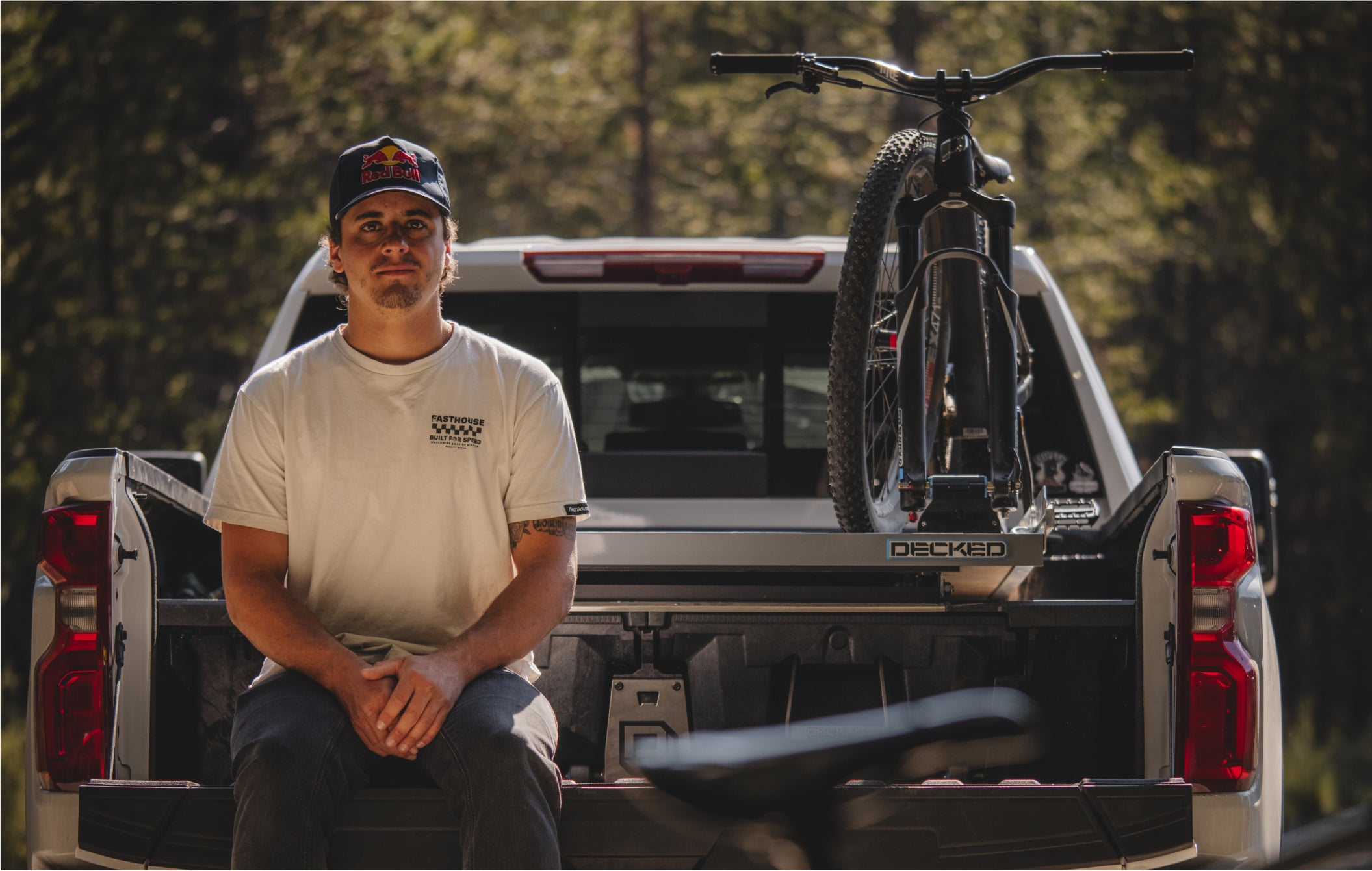 Carson Storch sitting on his tailgate in front of his DECKED gear with his bike mounted on top.