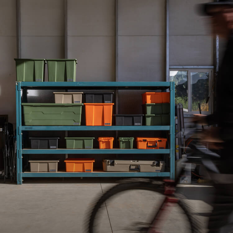 Storage rack with various sizes and colors of bins and cases in a garage setting