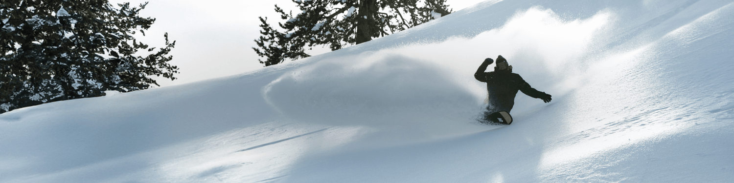 Curtis Ciszek snowboarding down a snowy slope with trees in the background