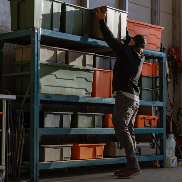 Person organizing ultra-rugged Payloader storage bins on a shelf in a garage.