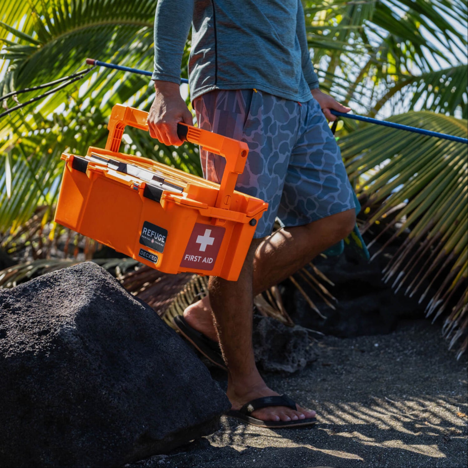 A man carrying his Improved First Aid Kit onto the beach.