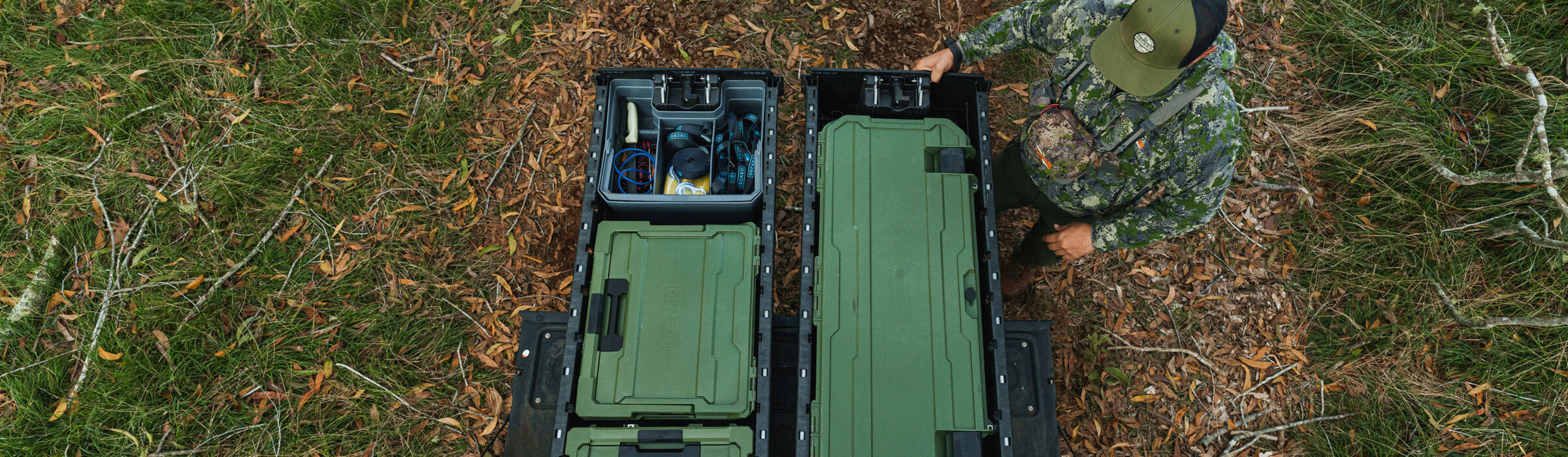 A man in camo admiring how organized his DECKED Drawer System is due to his collection of Ranger Green D-co Cases.