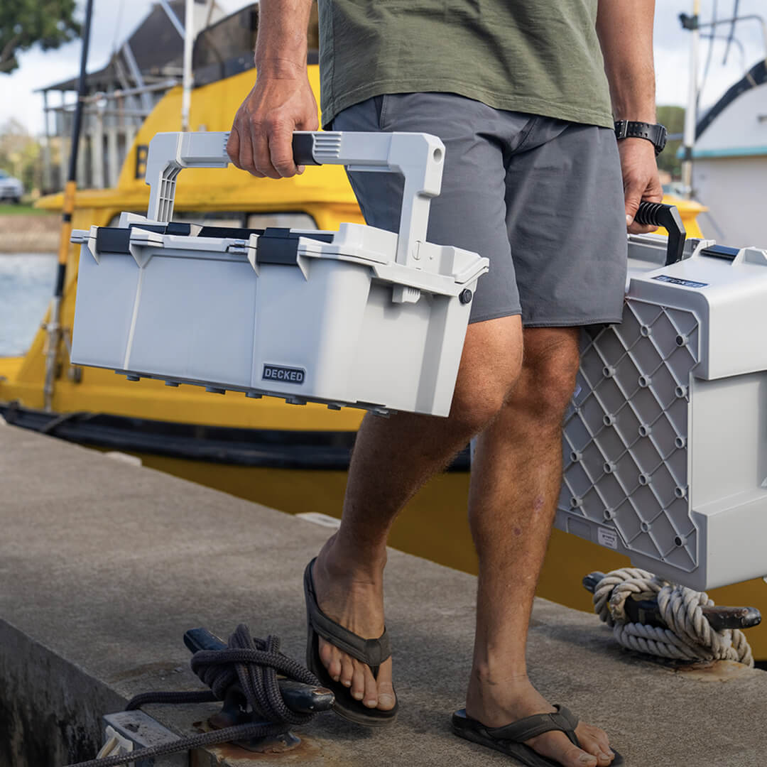 A many carrying two Cool Gray D-co Cases through a marina.