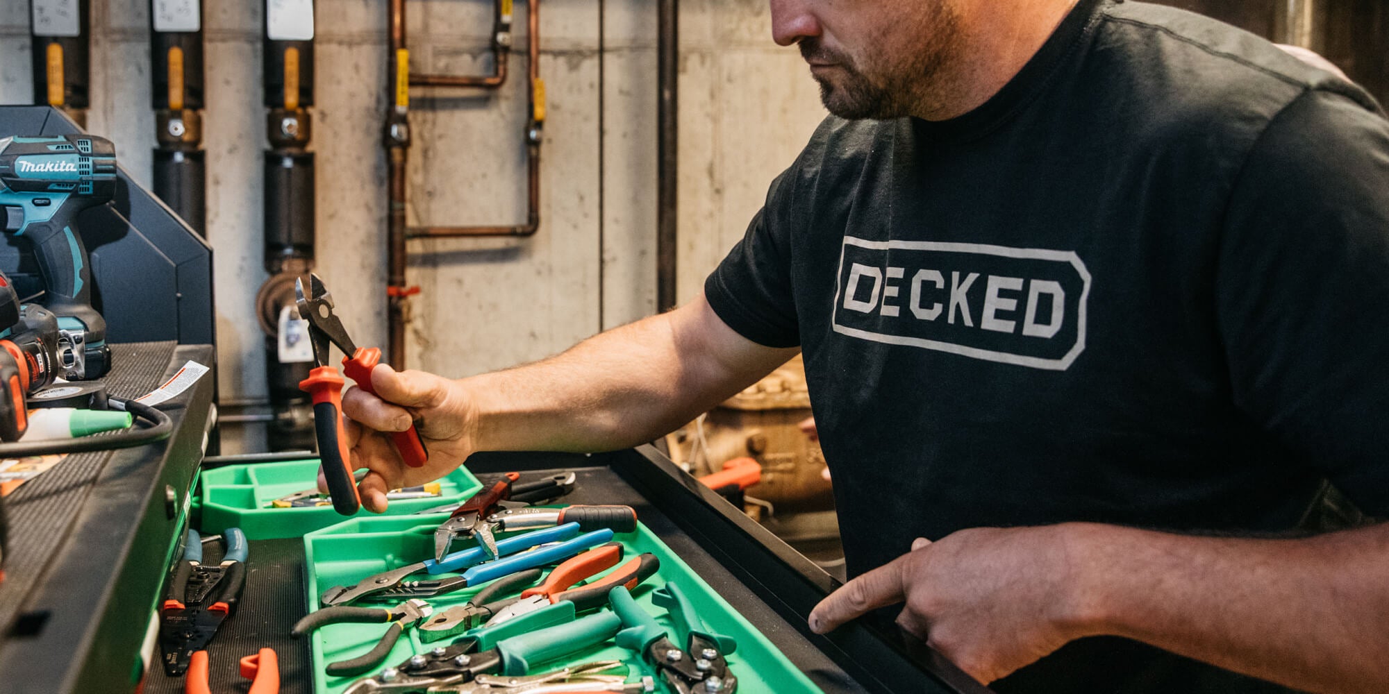 Man organizing tools in a workshop with 'Decked' branded shirt