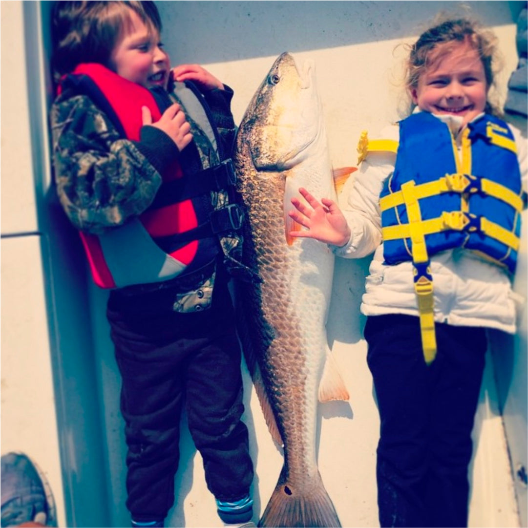 David Mangum's kids laying next to a fish just as tall as they are.