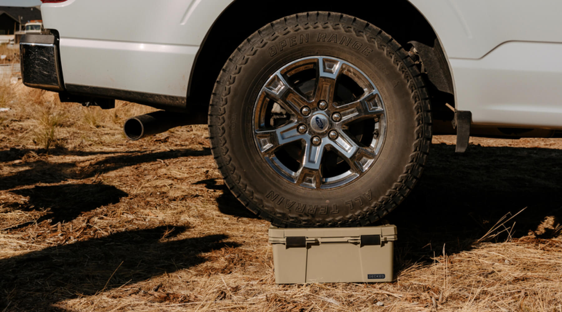 A Tacoma driving over a D-co case, its wheel balanced perfectly on top of the sturdy Sixer.