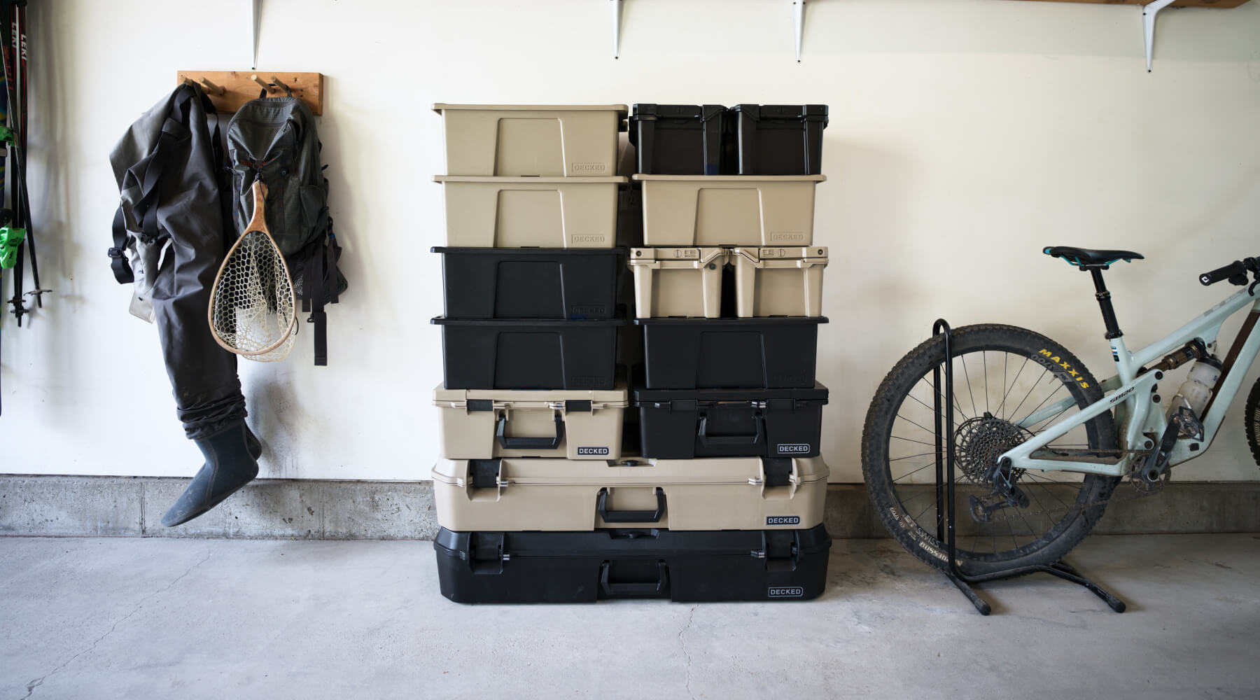 A stack of black and tan D-co Cases of all types stacked 7-high in a garage.