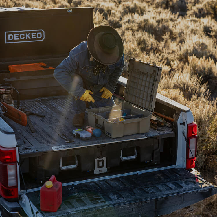 Person organizing tools in a Halfrack on a truck bed with a DECKED Drawer System and Tool Box.