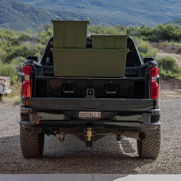 Back of a black pickup truck with green storage boxes and a Drawer System in a desert setting