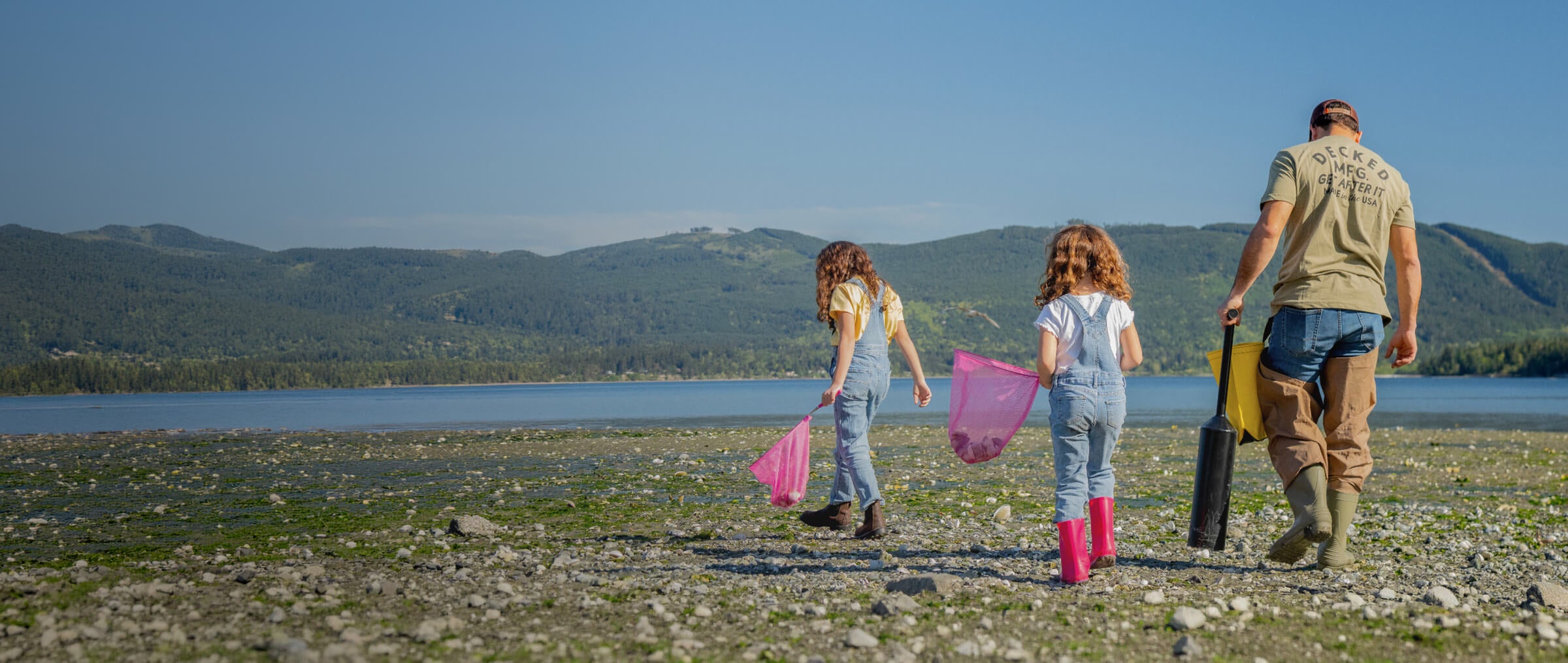 A DECKED Dad walking the beach, enjoying his time off with his two little girls, collecting sea shells in pink butterfly nets.