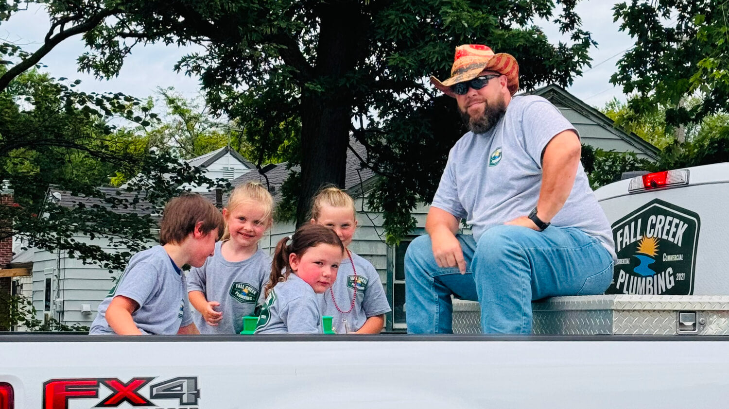 Another 2025 DTO winner, sitting in the back of a truck with his kids, with his 'Fall Creek Plumbing' logo visible.
