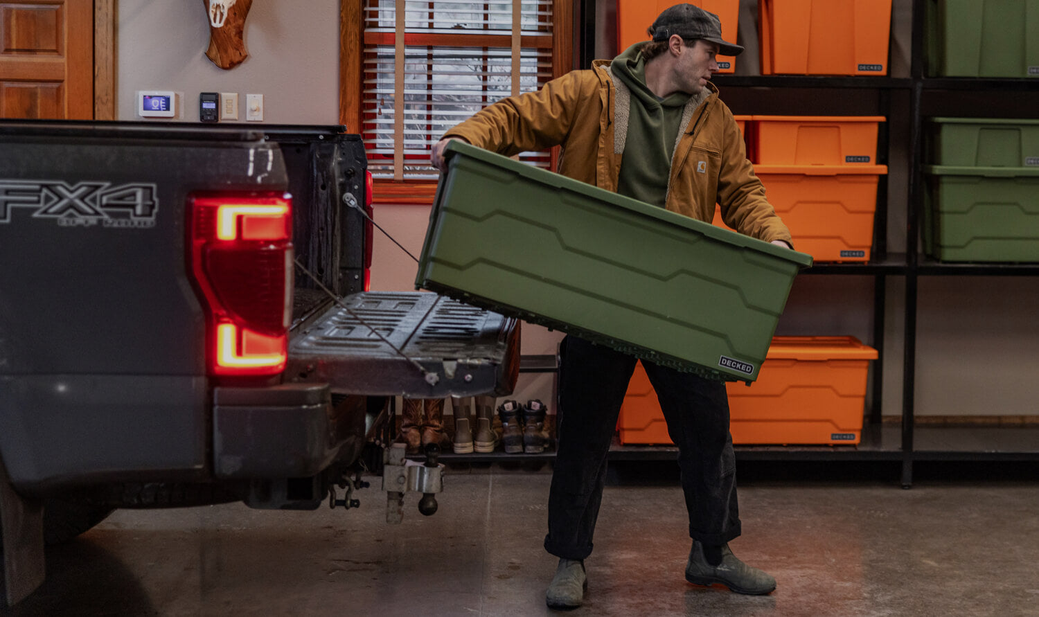 Person loading a green storage Payloader 133 bin into the back of a truck in a garage.