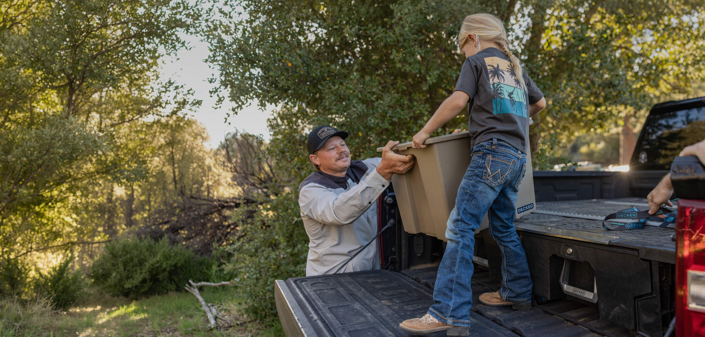 A dad and his daughter unloading the back of his truck of camping supplies for their weekend excursion.